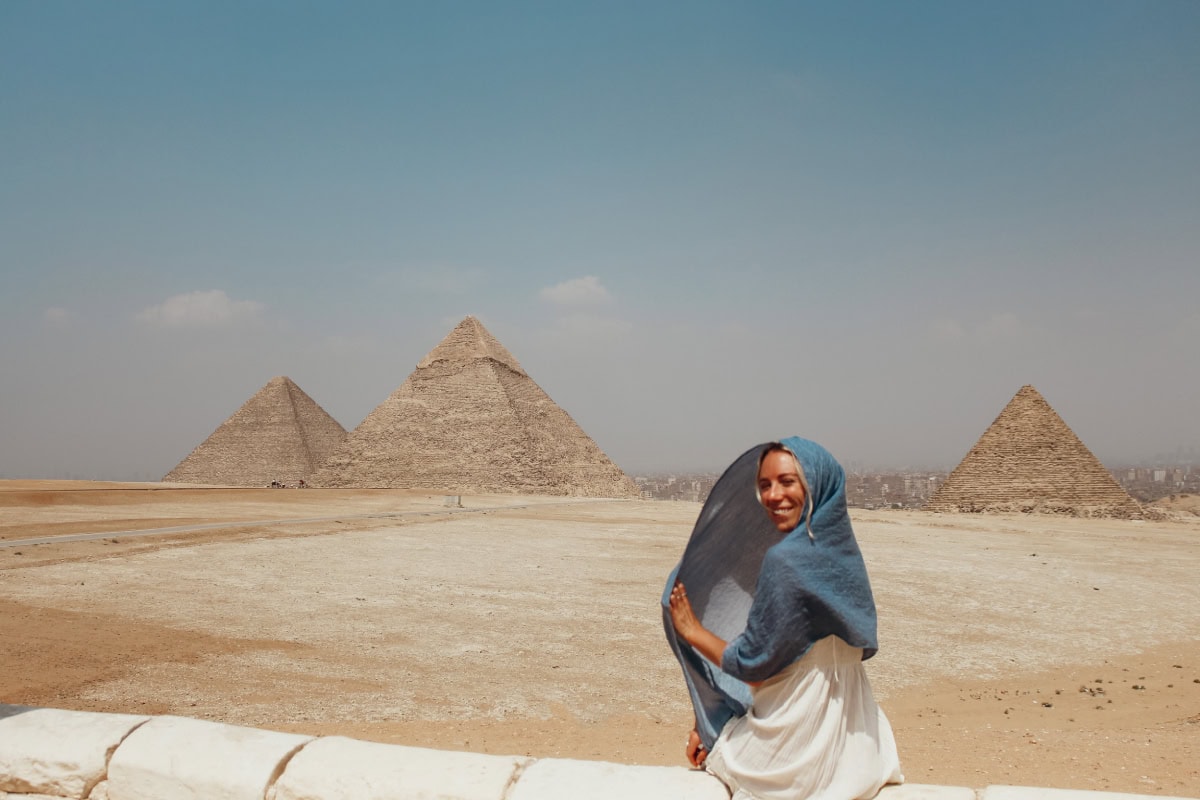 girl sitting in front of the pyramids in Giza, wondering what to wear in Egypt as a woman