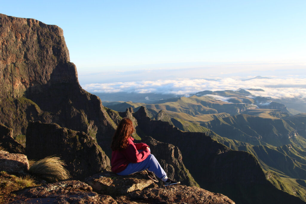 girl sitting on top of a mountain and waterfall in South Africa